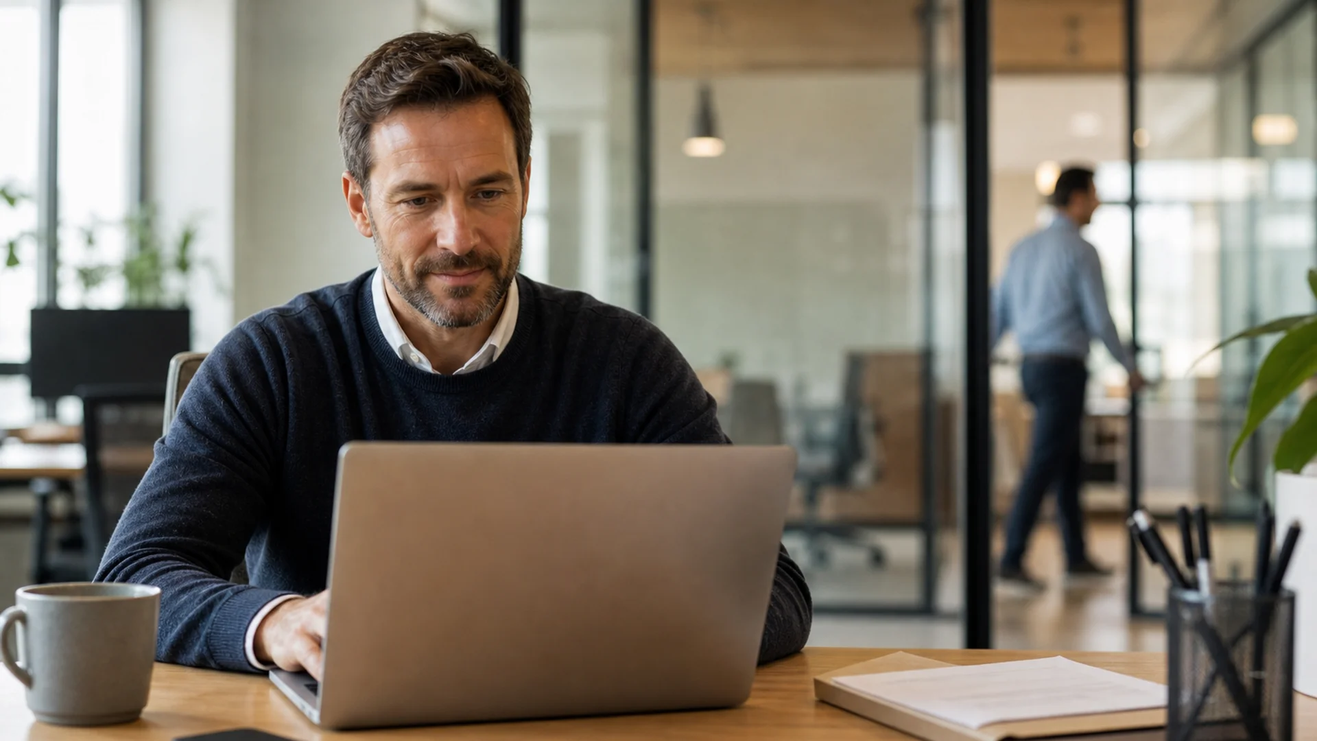 Portails clients et partenaires pour les opérations B2B Responsable des opérations utilisant un portail client B2B sur un ordinateur portable dans un bureau professionnel baigné de lumière naturelle chaude